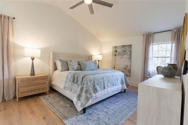 bedroom with ceiling fan, lofted ceiling, and light wood-type flooring