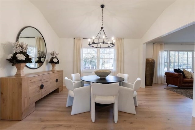 dining space featuring lofted ceiling, light wood-type flooring, an inviting chandelier, and a healthy amount of sunlight