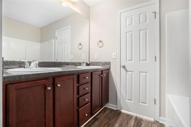 222 Ben Ln, Fairburn, GA 30213 - full bathroom with double vanity, wood finished floors, baseboards, and shower / tub combination