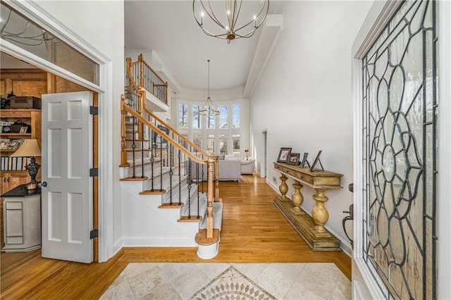 entrance foyer with a notable chandelier, crown molding, and wood-type flooring