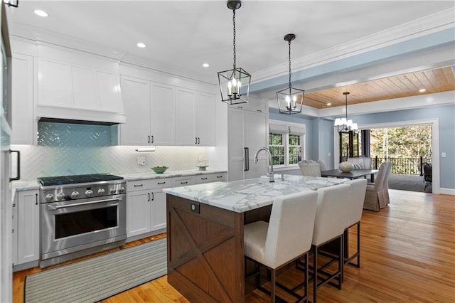 1658 E Clifton Rd NE, Atlanta, GA 30307 - kitchen with stainless steel stove, decorative backsplash, white cabinetry, open floor plan, and a breakfast bar area