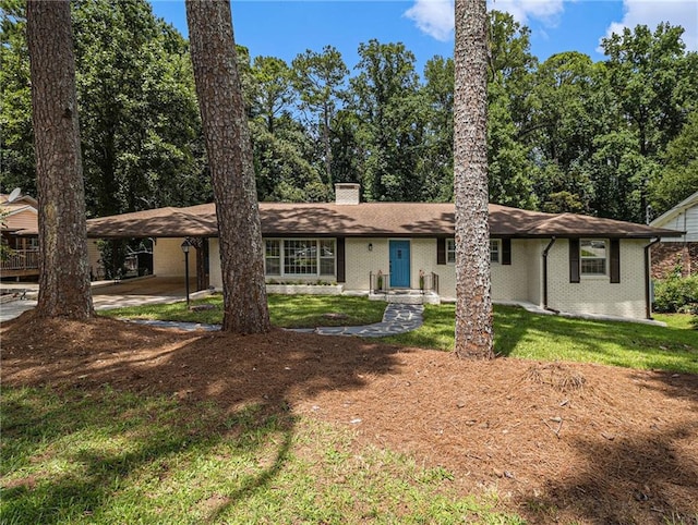 ranch-style home featuring brick siding, an attached carport, a chimney, and a front lawn