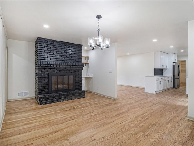 unfurnished living room with light wood finished floors, visible vents, recessed lighting, and a notable chandelier