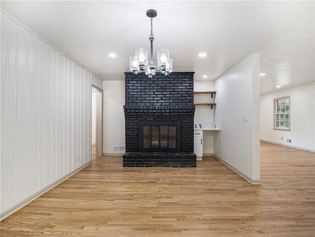 unfurnished living room with visible vents, light wood finished floors, recessed lighting, a fireplace, and a chandelier