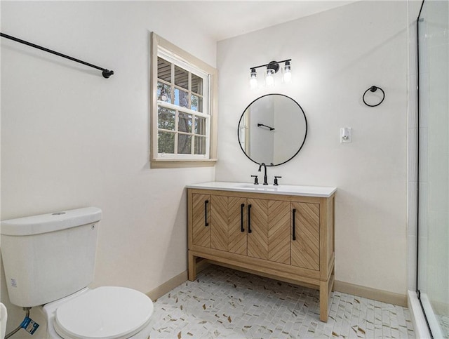 bathroom with vanity, a shower with shower door, toilet, and baseboards