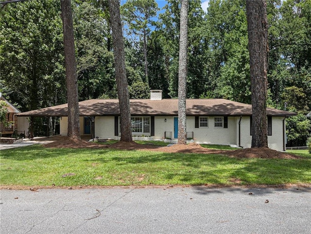 single story home featuring an attached carport, brick siding, a chimney, and a front yard