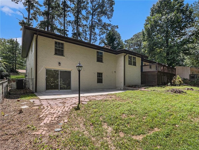 rear view of property with brick siding, fence, a lawn, a deck, and a patio area