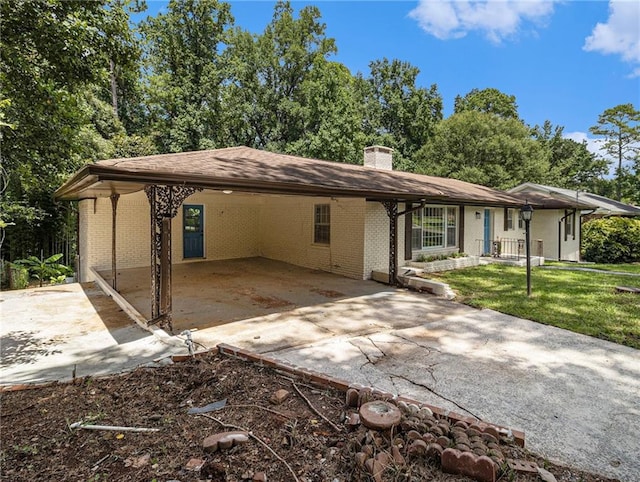 ranch-style home with an attached carport, a front yard, brick siding, and driveway