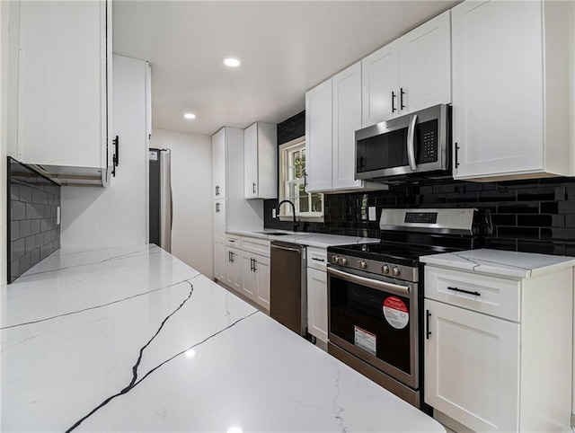 kitchen featuring a sink, white cabinets, light stone counters, and stainless steel appliances