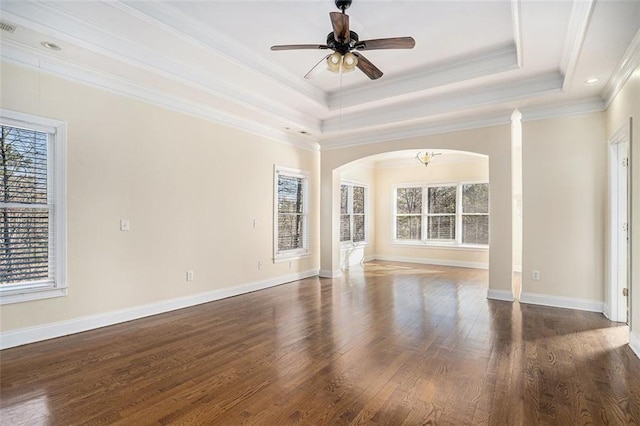 empty room with ceiling fan, crown molding, dark hardwood / wood-style floors, and a tray ceiling