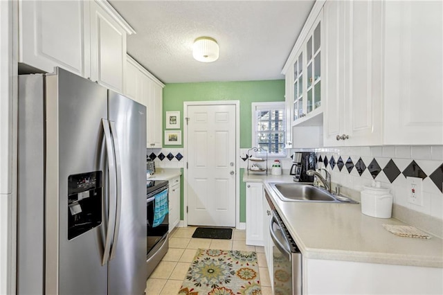 kitchen with white cabinets, sink, light tile patterned floors, and stainless steel appliances