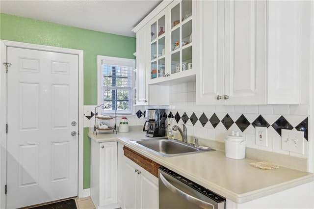 kitchen featuring decorative backsplash, sink, white cabinets, and dishwasher