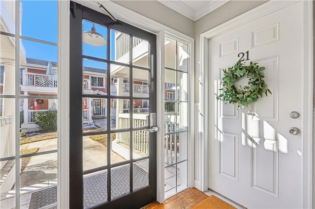 doorway with crown molding, a healthy amount of sunlight, and hardwood / wood-style flooring