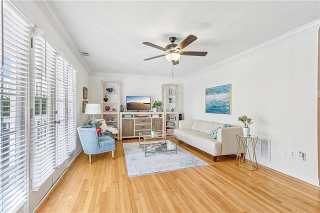 living room with ceiling fan, crown molding, and light wood-type flooring