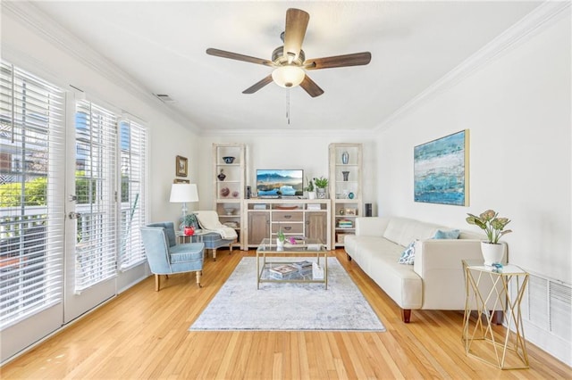 living room featuring ceiling fan, ornamental molding, and light hardwood / wood-style floors