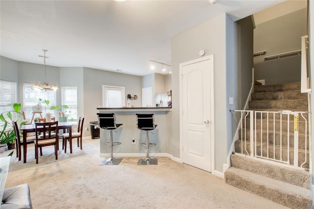interior space featuring a kitchen bar, an inviting chandelier, baseboards, and carpet floors