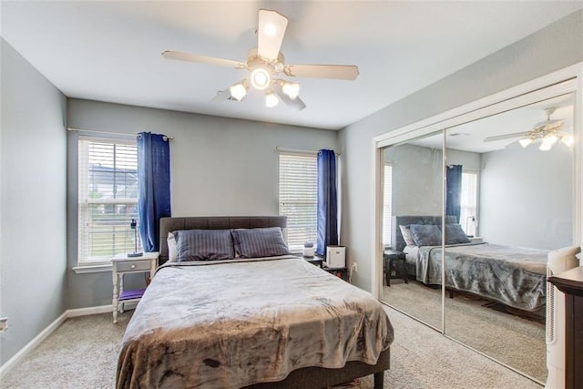 bedroom with a closet, light colored carpet, baseboards, and ceiling fan