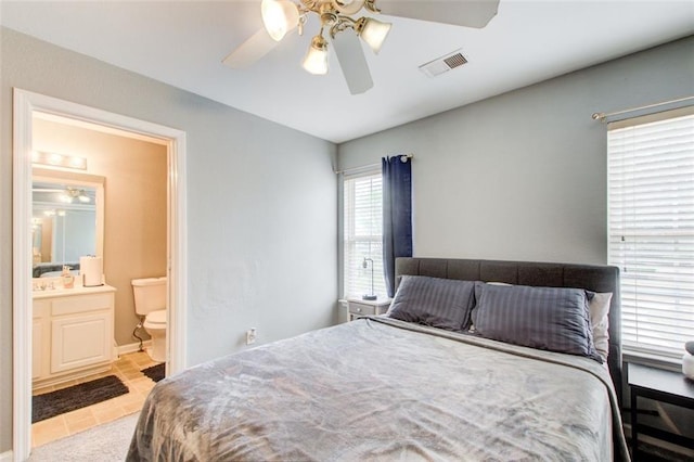 bedroom featuring visible vents, ensuite bathroom, tile patterned flooring, and a ceiling fan