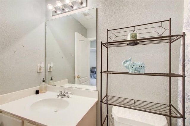 bathroom featuring visible vents, a textured wall, and vanity