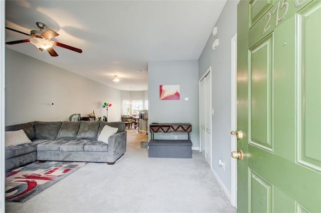 living area with ceiling fan, light colored carpet, and baseboards