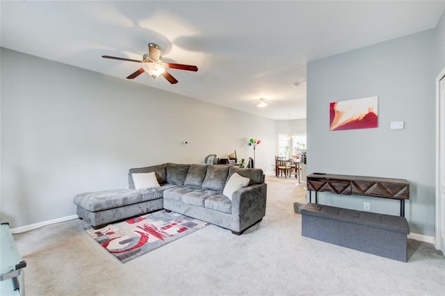 living area with baseboards, a ceiling fan, and carpet