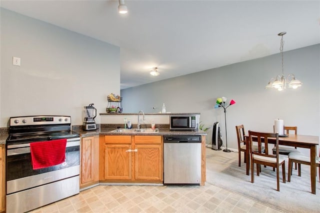 kitchen with a notable chandelier, a peninsula, stainless steel appliances, pendant lighting, and a sink