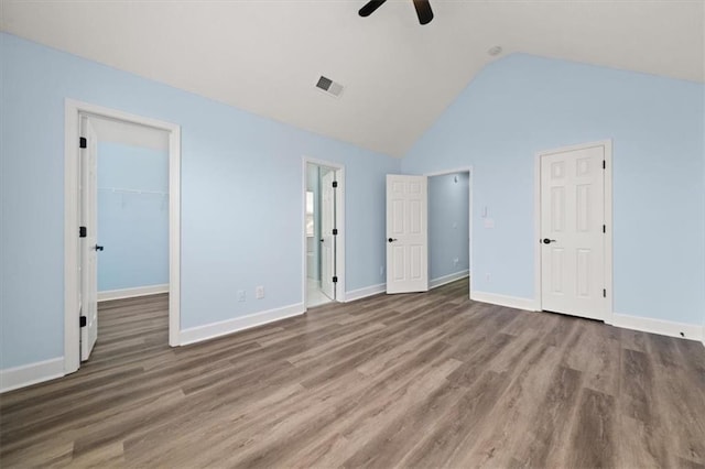 unfurnished bedroom with a closet, a spacious closet, dark hardwood / wood-style floors, high vaulted ceiling, and ceiling fan