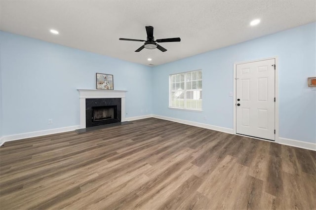 unfurnished living room featuring dark wood-type flooring and ceiling fan