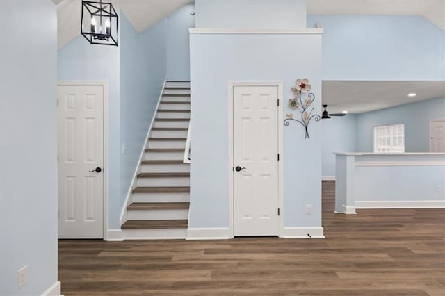 stairway with high vaulted ceiling, hardwood / wood-style floors, and a notable chandelier