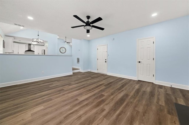 unfurnished living room featuring ceiling fan with notable chandelier and dark hardwood / wood-style floors