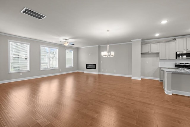 interior space featuring crown molding, visible vents, light wood finished floors, and ceiling fan with notable chandelier
