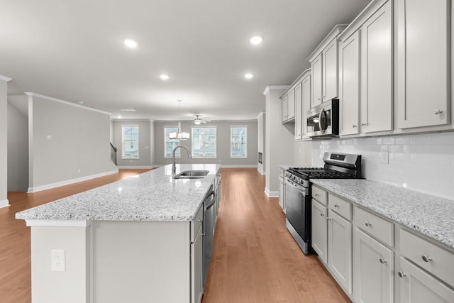 kitchen with baseboards, a sink, ceiling fan, appliances with stainless steel finishes, and light wood-style flooring