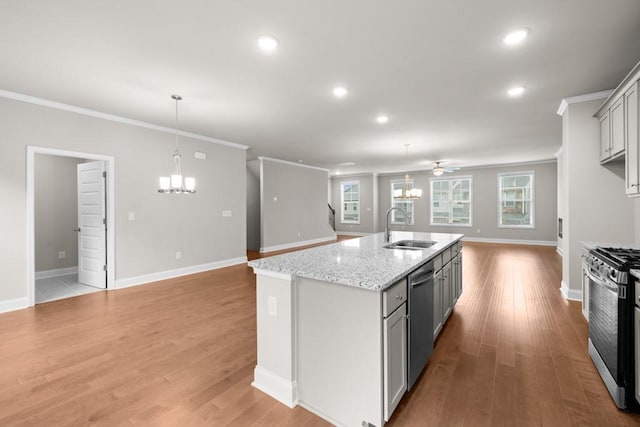 kitchen with an inviting chandelier, a sink, open floor plan, appliances with stainless steel finishes, and crown molding