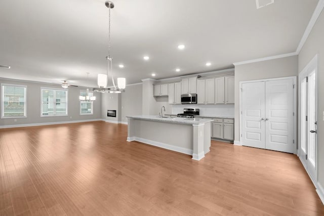 kitchen with ornamental molding, recessed lighting, open floor plan, appliances with stainless steel finishes, and a sink