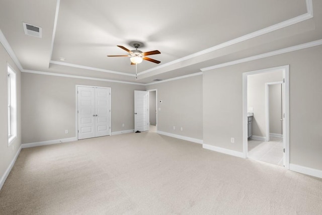 unfurnished bedroom with visible vents, baseboards, ornamental molding, a tray ceiling, and light carpet