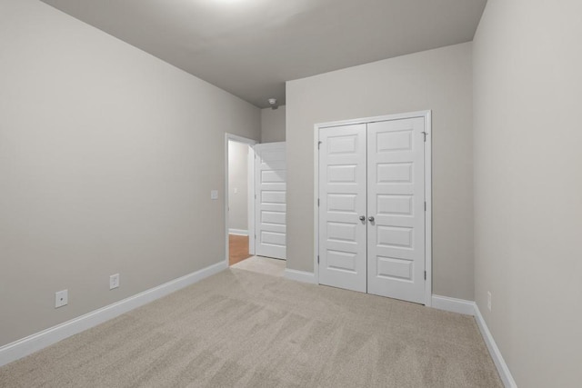 unfurnished bedroom with carpet flooring, a closet, and baseboards
