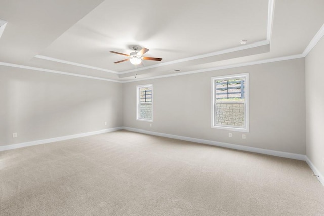 spare room with crown molding, baseboards, a raised ceiling, and a ceiling fan