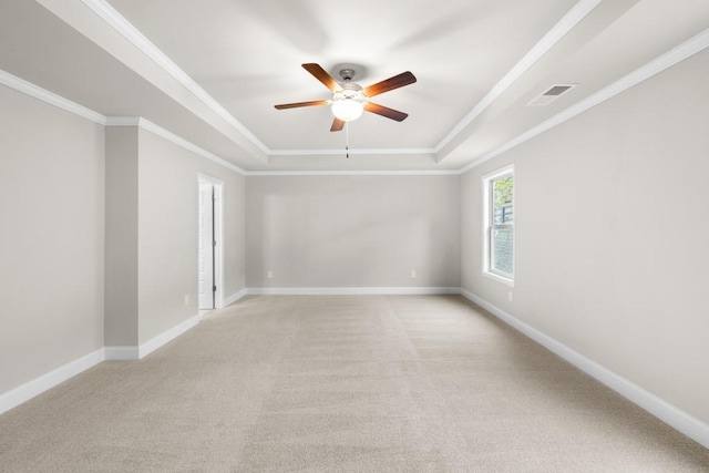 spare room with light carpet, visible vents, a tray ceiling, and ceiling fan