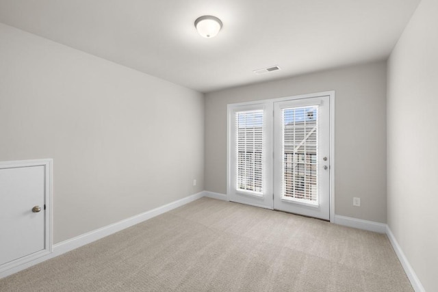 empty room featuring light carpet, visible vents, and baseboards
