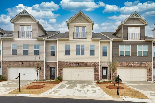 view of property featuring brick siding, an attached garage, driveway, and a balcony