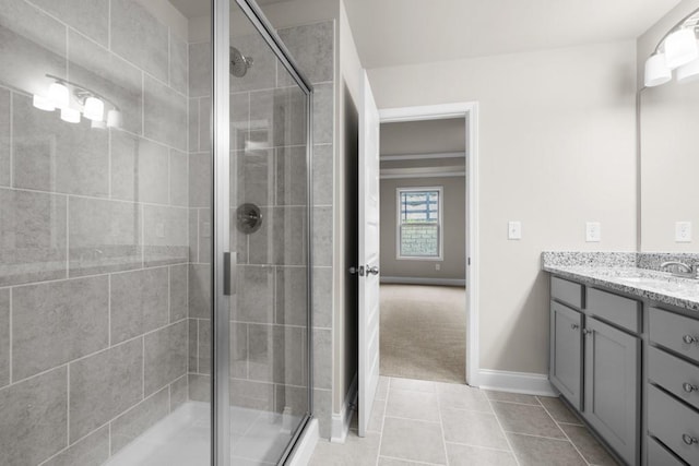 bathroom with a stall shower, vanity, baseboards, and tile patterned floors
