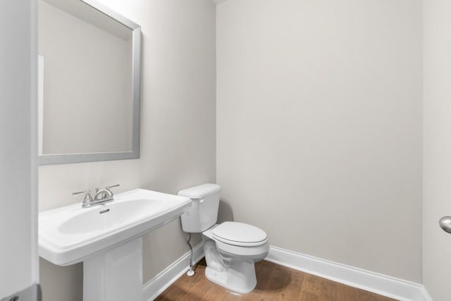 bathroom featuring toilet, wood finished floors, and baseboards