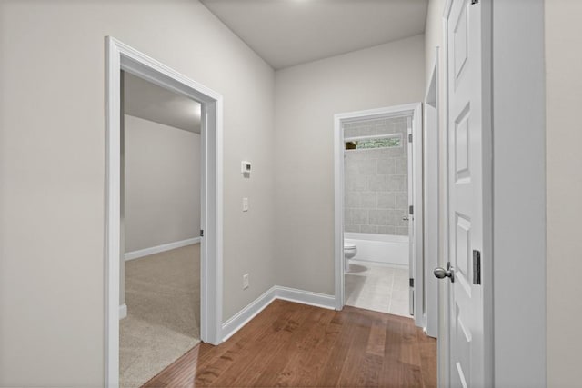corridor featuring baseboards and dark wood finished floors