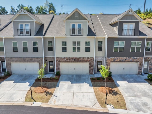 multi unit property with concrete driveway, stone siding, and an attached garage