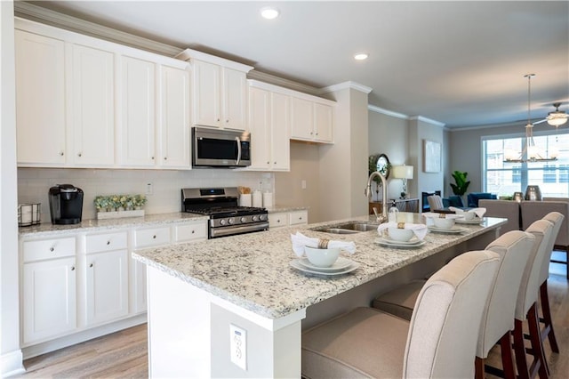 kitchen featuring a breakfast bar, crown molding, stainless steel appliances, white cabinets, and a sink