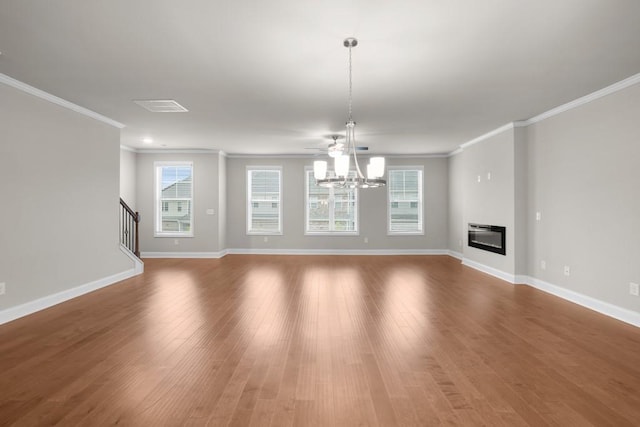 unfurnished living room with crown molding, baseboards, an inviting chandelier, and a healthy amount of sunlight