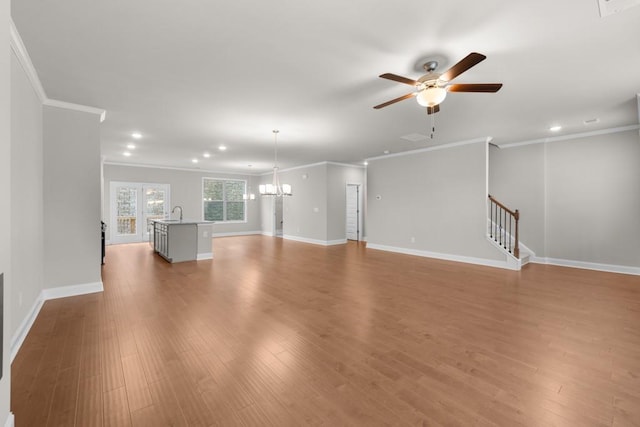 unfurnished living room featuring recessed lighting, light wood finished floors, ceiling fan with notable chandelier, and crown molding