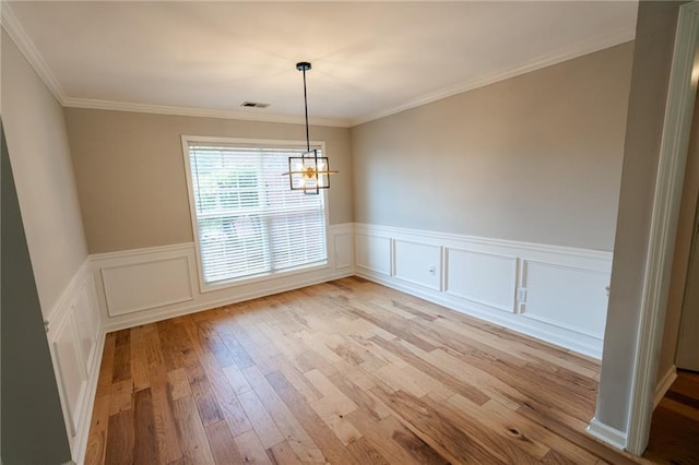 1200 Martins Chapel Ln SE, Lawrenceville, GA 30045 - unfurnished dining area with light wood finished floors, a chandelier, wainscoting, crown molding, and a decorative wall