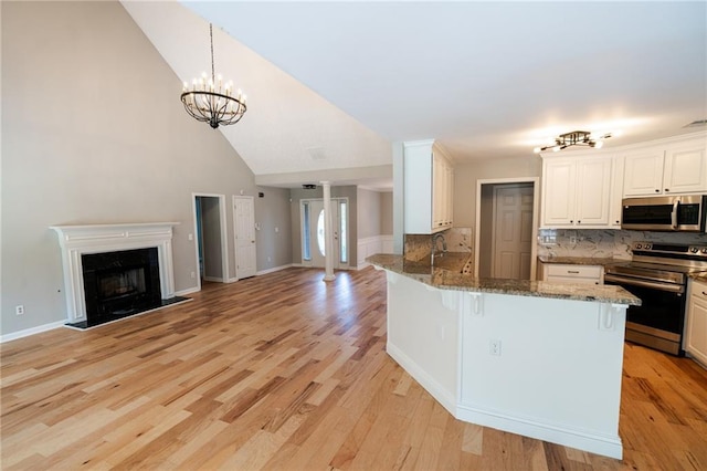 1200 Martins Chapel Ln SE, Lawrenceville, GA 30045 - kitchen with appliances with stainless steel finishes, open floor plan, a kitchen bar, stone countertops, and a fireplace with raised hearth