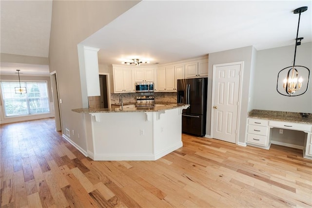 1200 Martins Chapel Ln SE, Lawrenceville, GA 30045 - kitchen with stainless steel appliances, a chandelier, a breakfast bar area, backsplash, and light stone counters